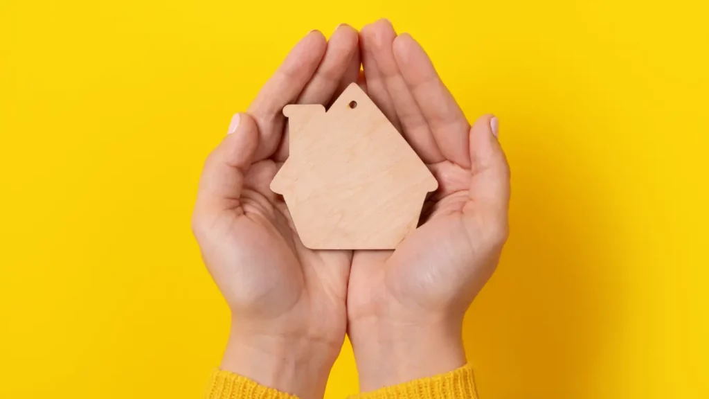 Person holding wooden home cutout